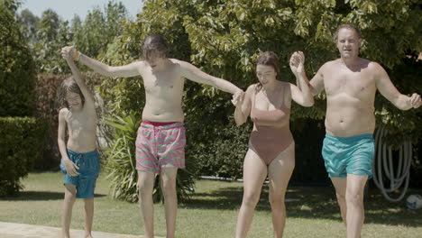 cheerful parents and kids holding hands and running into swimming pools together