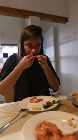 una mujer comiendo camarones.