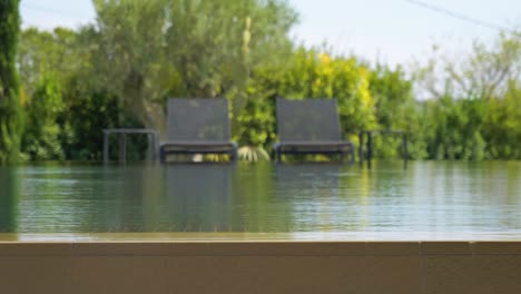 static shot of water overflowing a pool with sun loungers out of focus