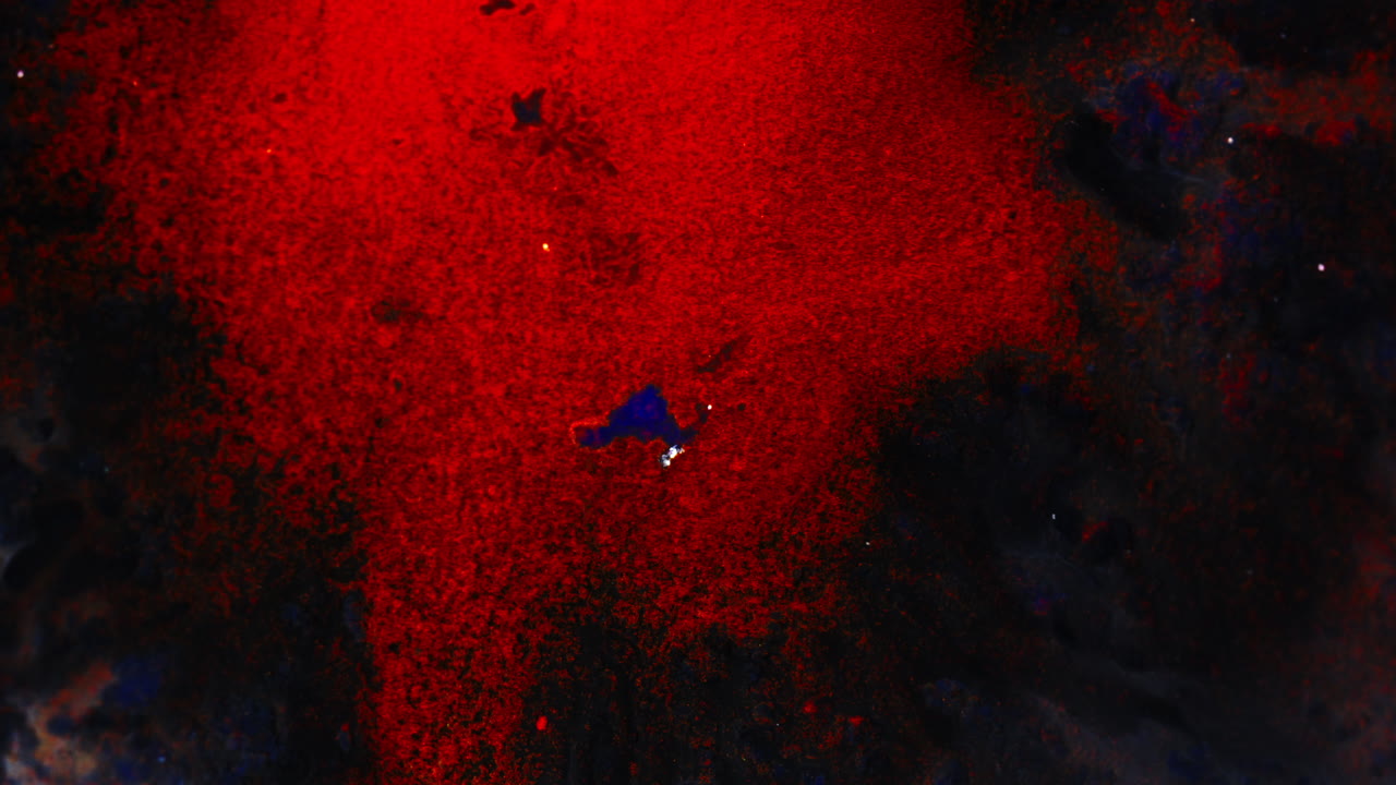 Red ink floating in a dark space, creating an abstract and surreal atmosphere