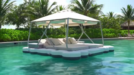 relaxing floating lounge under a canopy amidst lush palm trees and crystal-clear water for ultimate leisure in a serene tropical paradise