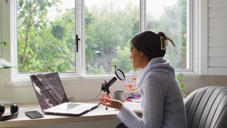 video de una mujer biracial participando en una entrevista en línea en una computadora portátil en casa
