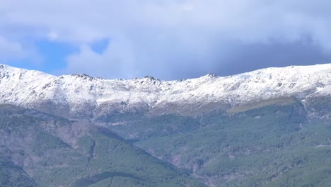 166mm-filming-with-a-drone-of-a-part-of-the-Gredos-mountains-where-there-is-a-lush-pine-forest-and-its-peaks-are-snow-capped-there-is-a-sky-with-clouds-in-the-Tietar-valley-Avila-Spain