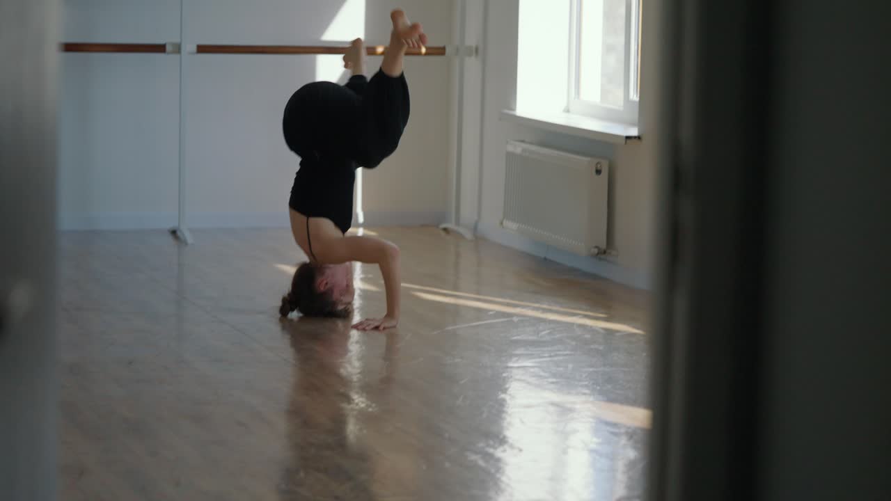 A woman doing a headstand in a dance studio