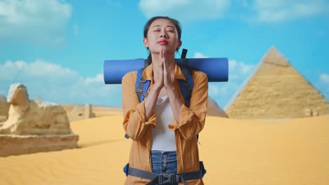 asian female hiker with mountaineering backpack pray for something while traveling in pyramid of giza