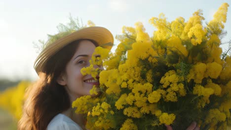 young woman wearing straw hat standing in sunlit field, gently holding large bouquet of vibrant mimosa flowers, radiating joy and serenity during springtime moment
