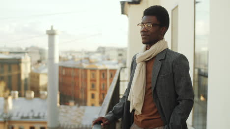 Alegre-Hombre-De-Negocios-Afroamericano-Posando-Para-La-Cámara-En-La-Terraza-De-La-Azotea