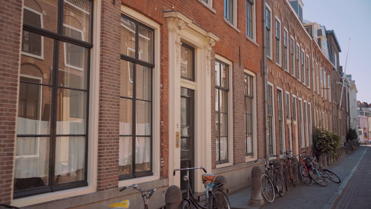 Moving Through The Sidewalk In Utrecht, Netherlands With Bicycles Parked In Front Of Modern Brick Buildings - dolly shot
