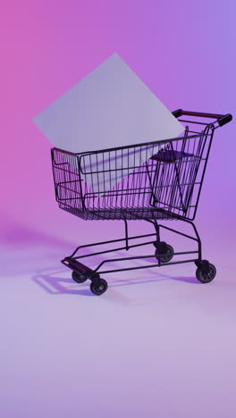 Vertical video of shopping trolley with white canvas with copy space over pink neon background
