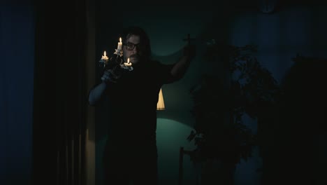 man with candelabra and cross in a dark, mysterious room