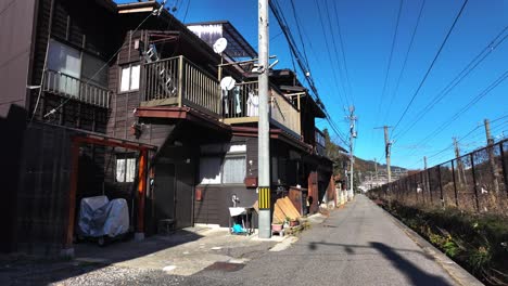 quiet residential street with traditional wooden houses and overhead power lines in narai juku, japan, on a clear, sunny day