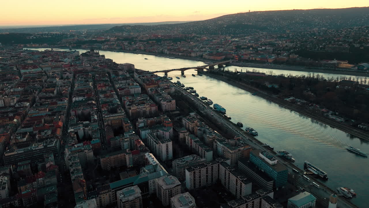 Vista aerea al tramonto di Budapest, Ungheria, con il fiume Danubio che attraversa la città. Luoghi iconici, dolci colline e quartieri residenziali nella calda luce della sera e un'atmosfera di pace