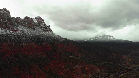 aerial shot of the utah red rock mountains covered in snow on a cloudy day
