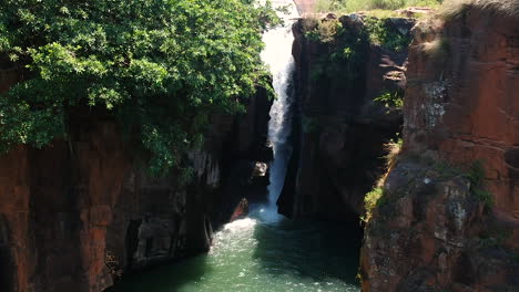 Toma-Aérea-De-Un-Río-Con-Una-Cascada-En-La-Jungla-De-Sudáfrica