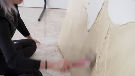 young female painter sitting on the floor working on her canvas in the studio - close up