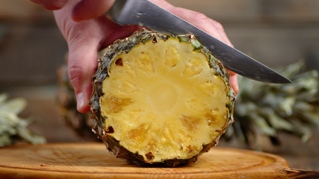 손은 익은 파인애플을 절단판에 잘라낸다.