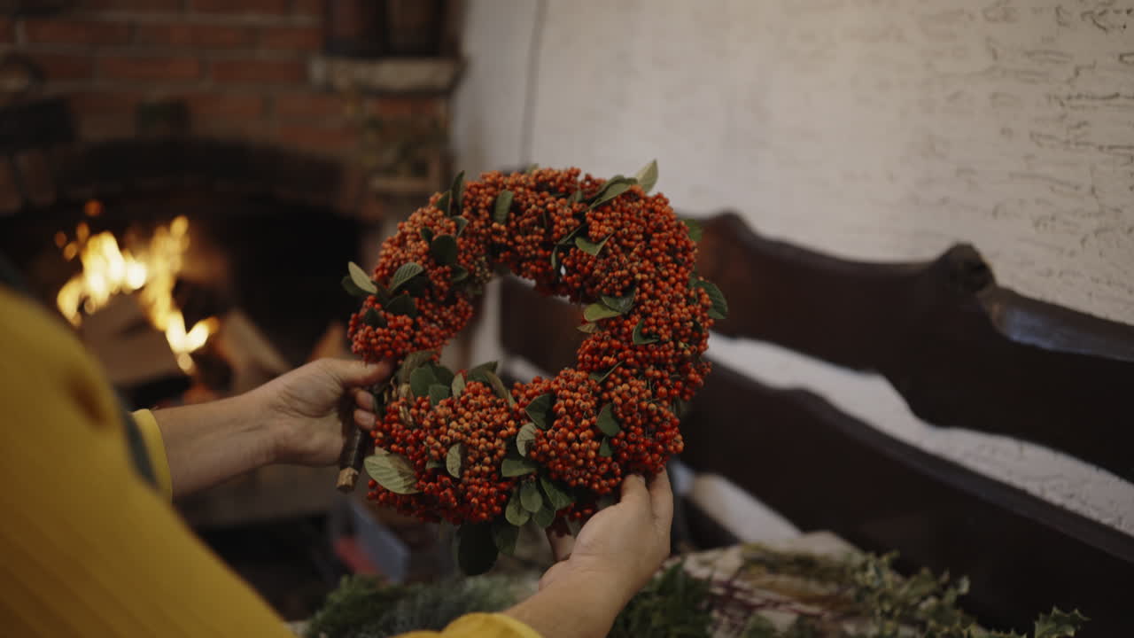 Woman holding a beautiful handmade wreath by the fireplace