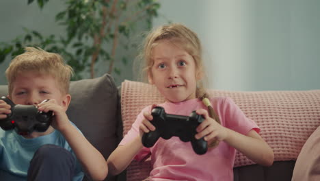Toothless-girl-and-blond-boy-play-video-game-sitting-on-sofa