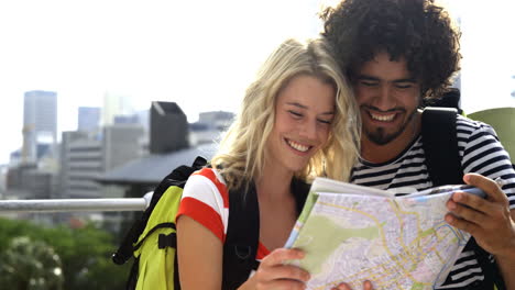 una feliz pareja de hipsters mirando un mapa y señalando la dirección