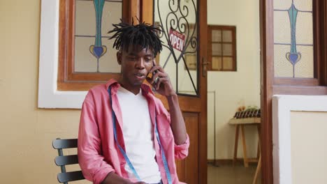 happy african american craftsman making phone call in leather workshop