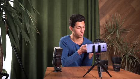 capacitación para fotógrafos principiantes, cursos en línea. un hombre musulmán graba una revisión de video de equipos fotográficos usando una aplicación en un teléfono inteligente. la estructura de la cámara y la lente.