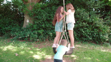 grupo de niños jugando en el columpio de neumáticos en el jardín