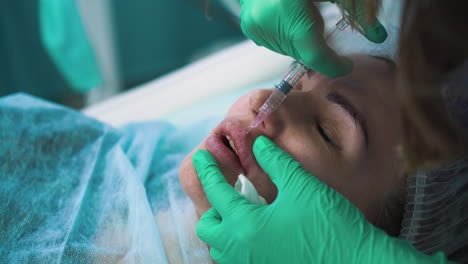 woman does injection for lips augmentation to woman closeup