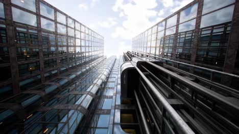 tall glass buildings reflect the bright sky as viewers look up at the impressive architecture. the urban landscape evokes a sense of wonder and modern design.