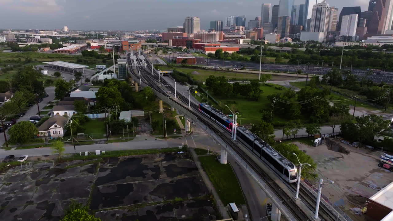 vista aérea siguiendo un tren ligero que se acerca al horizonte de houston, hora de oro
