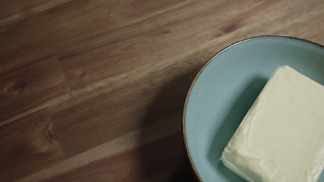 medium close shot of a fresh block of butter lying in a ceramic bowl