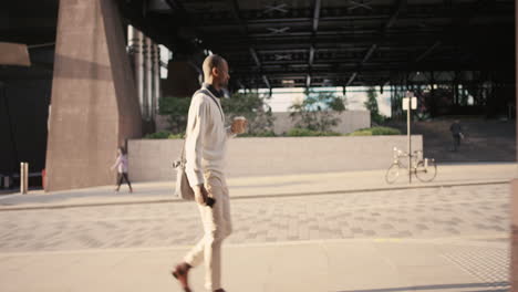 hombre de negocios afroamericano caminando por la ciudad usando un teléfono inteligente