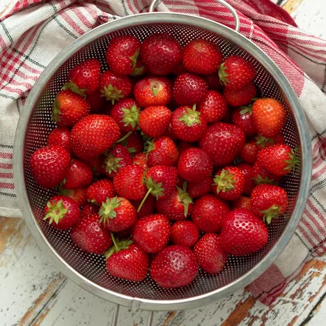 freshly harvested strawberries  metal colander filled with juicy fresh ripe strawberries on an table