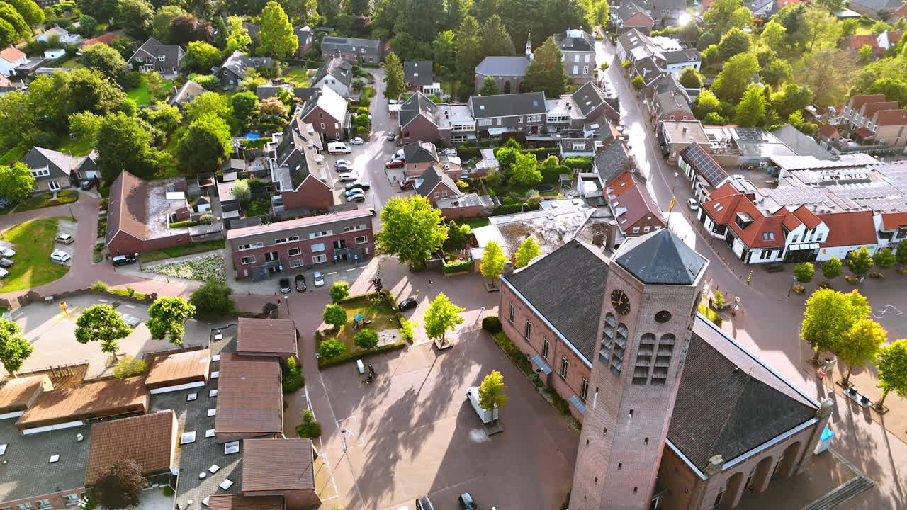 Drone view of Dutch village square with church tower. Aerial perspective of a Dutch village square featuring a brick church tower and surrounding streets
