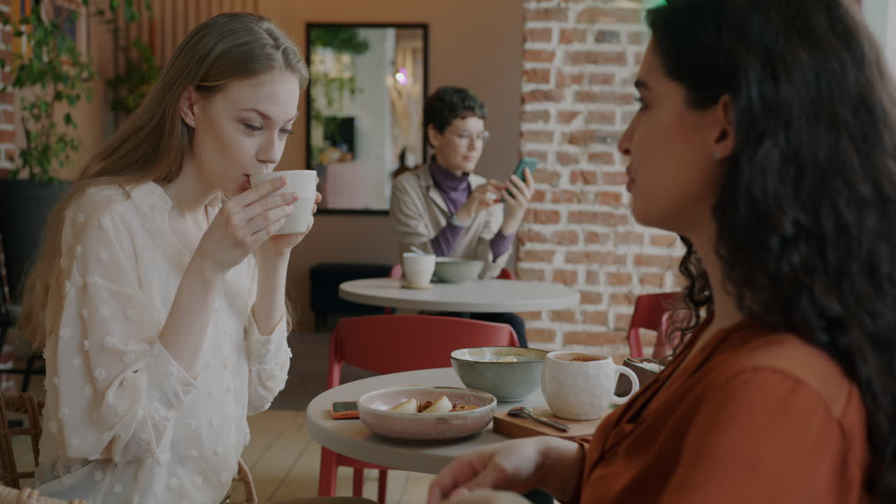 Women friends having coffee and conversation in a cafe