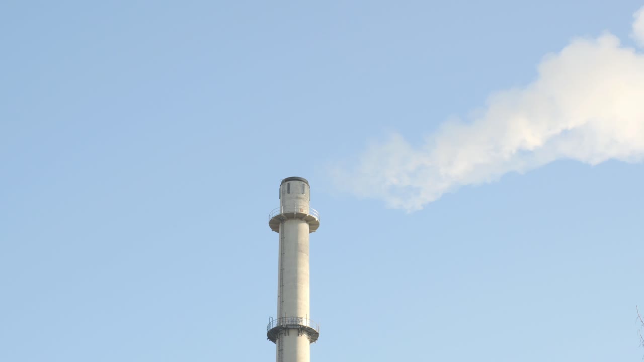 Emissions from a power plant smoke stack with blue sky in the background