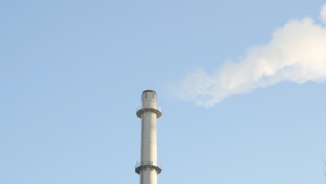 emissions from a power plant smoke stack with blue sky in the background