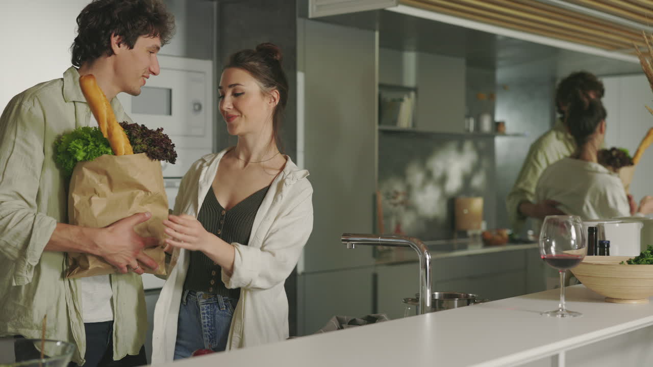 Coppia che disfa la spesa e prepara il cibo in una cucina moderna