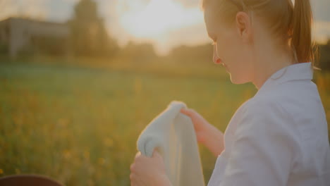 woman drapes blanket over baby at sunset in stroller
