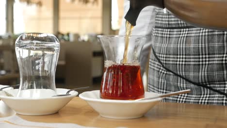 a person pouring turkish tea in a glass