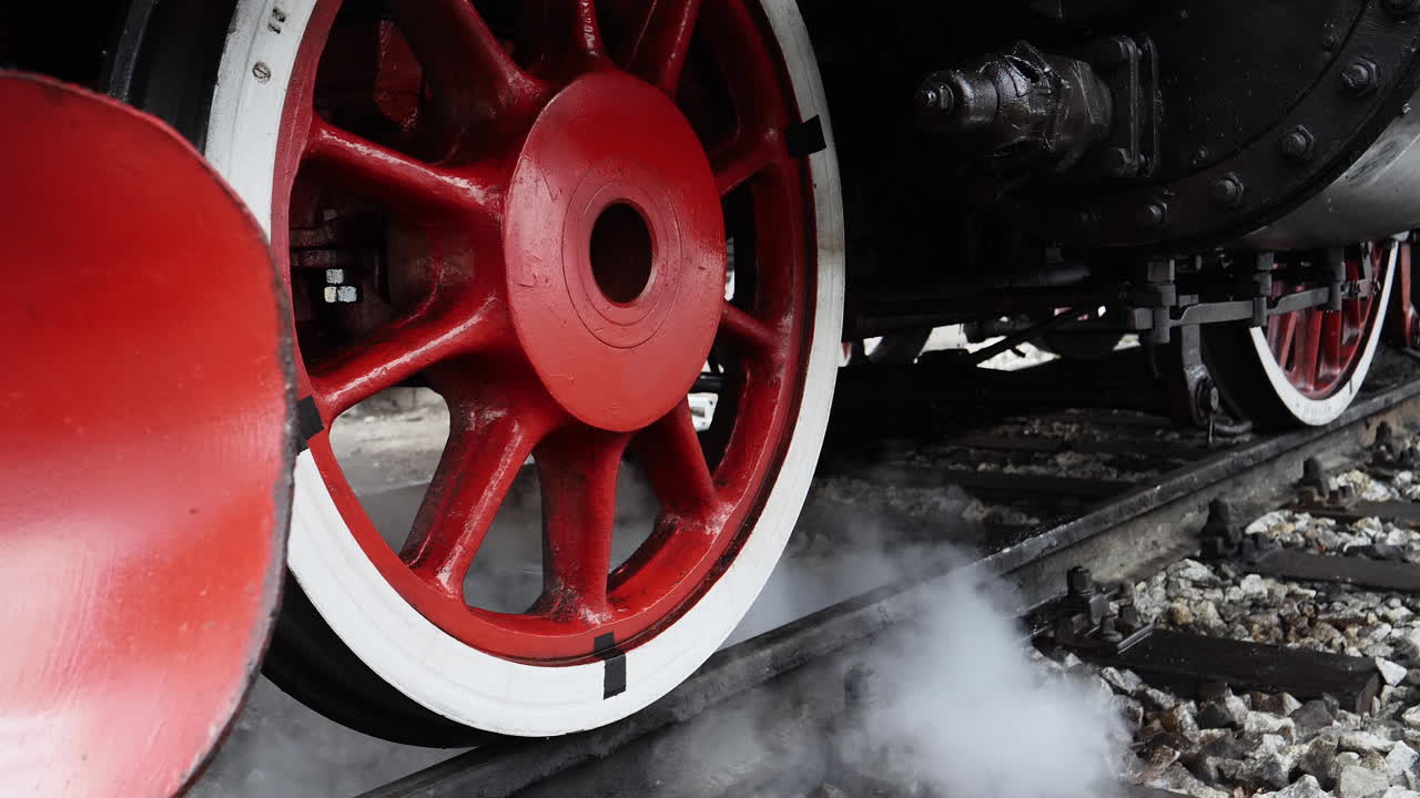 Detail of old coal powered train wheels and steam smoke puffing out
