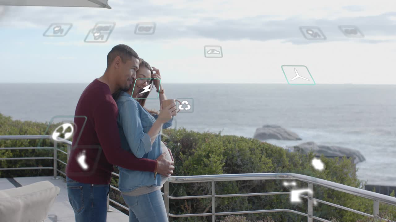 Woman holding mug, man approaching, cradling belly on deck, tech icons overlaying couple, bonding