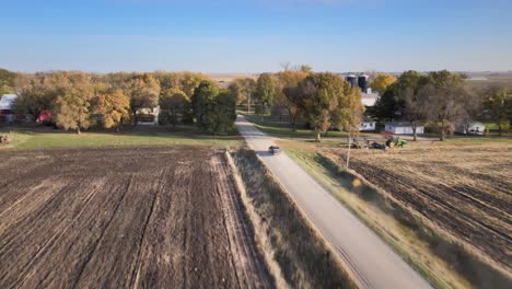 Luftdrohne-Nach-Aufnahme-Eines-Pickup-Trucks,-Der-Auf-Einer-Staubigen-Schotterstraße-Unter-Blauem-Himmel-Im-Ländlichen-Mittelwesten-Von-Iowa-Fährt