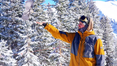 Snowboarder-feeds-bird-in-hand-Telluride-ski-resort-bluebird-fresh-deep-snow-powder-winter-Rocky-Mountains-Warren-Miller-Silverton-14er-Mt-Sneffels-Epic-Pass-Southern-Colorado-cinematic-follow