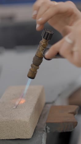 artisan soldering metal with a torch in a workshop