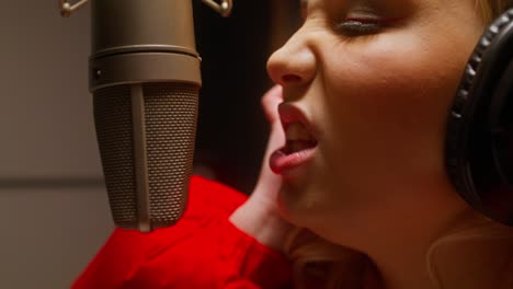 mujer cantando en un micrófono en un estudio de grabación