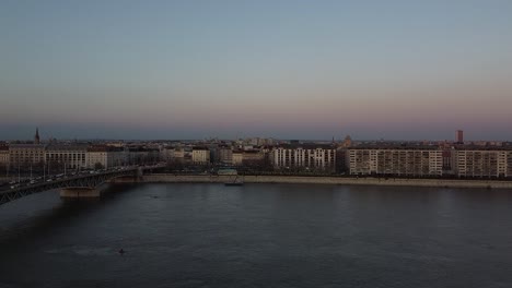 Aerial-view-of-Traffic-at-Bridge-above-River-Danube-During-Sunset-at-Budapest-with-the-City-in-the-Background