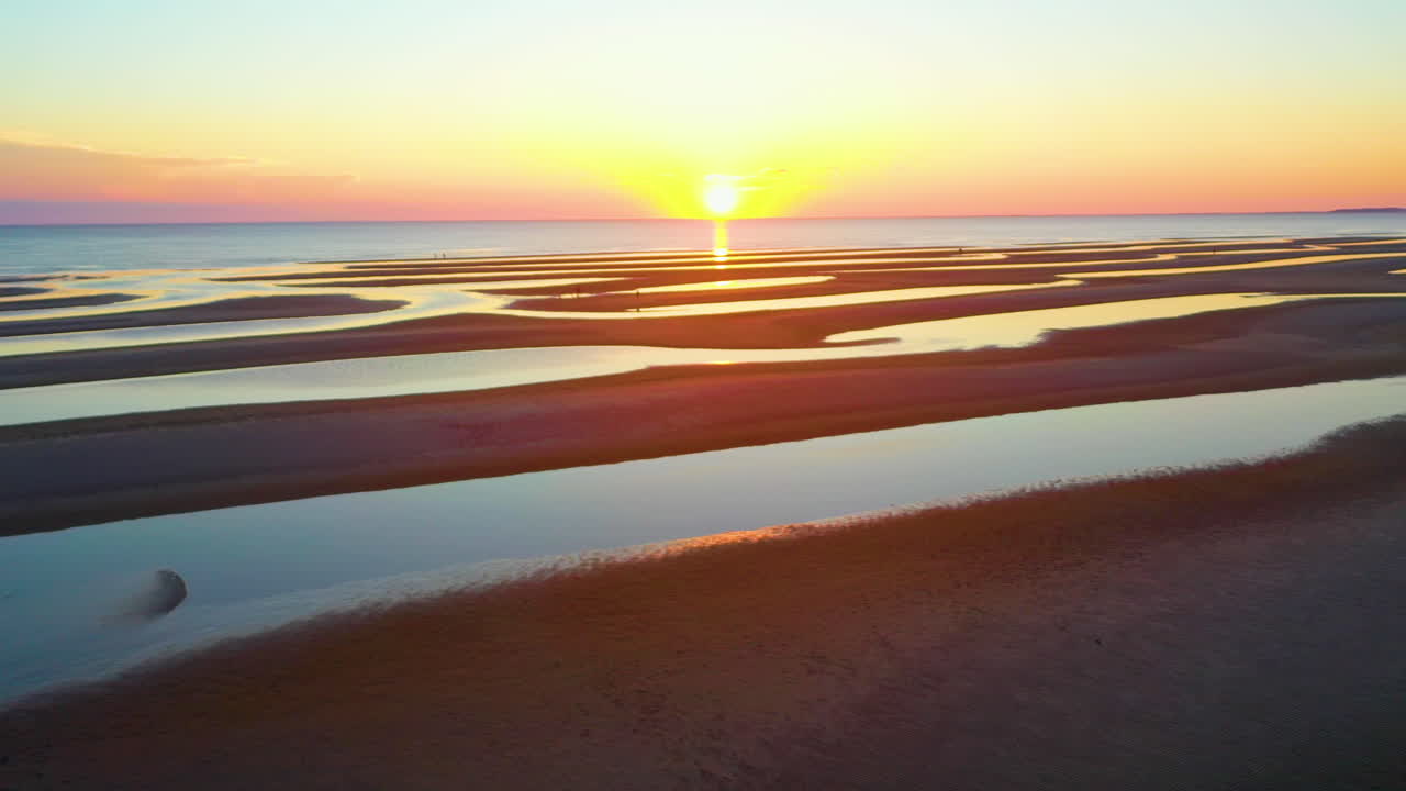 Aerial view of a beautiful sunset over a beach with sandbars and people