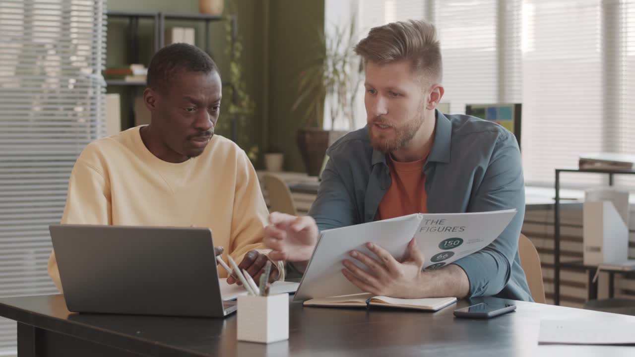 Two Diverse Startupers Planning Project Budget in Office