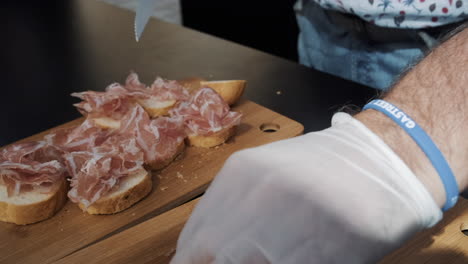 preparing prosciutto and bread appetizers