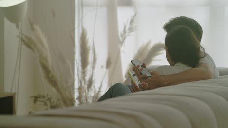 back view of happy couple watching mobile phones together.